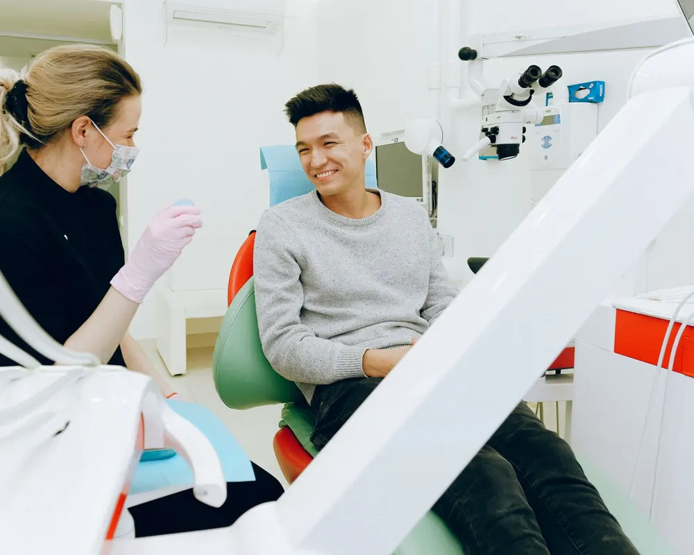 Dentista conversando com paciente sorridente no consultório